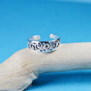 Peut inclure: Bague d'orteil en argent avec un motif délicat en spirale. La bague est ouverte et réglable pour s'adapter à la plupart des tailles.