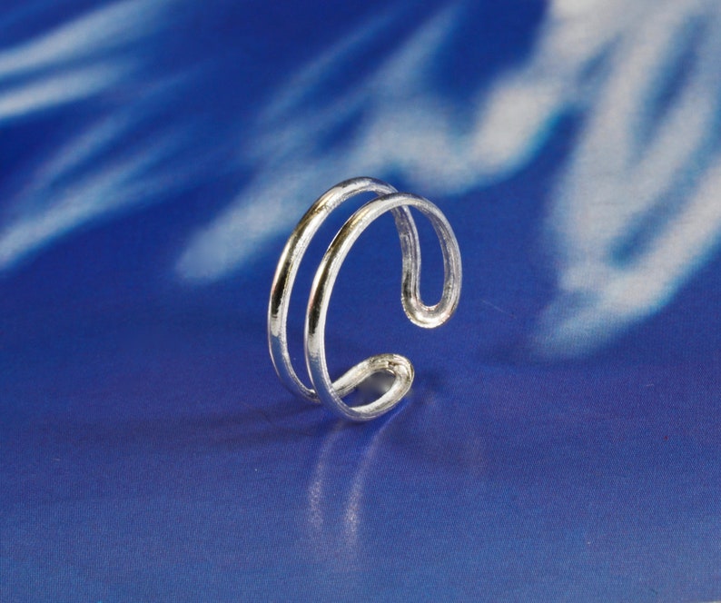 May include: A silver ring with a double band design. The ring is simple and elegant.