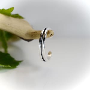 May include: A silver toe ring with two thin lines around the band.