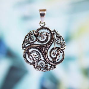 May include: Silver pendant with a Celtic Triskele design. The pendant is circular, featuring three interconnected spirals, detailed knotwork, and a bail for a chain. The design is intricate and ornate, with a polished finish. The pendant is suitable for a necklace.