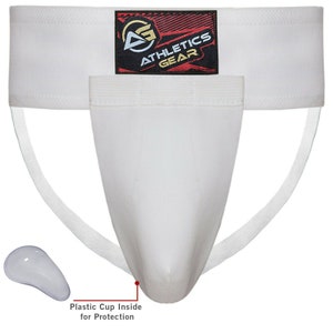 May include: White athletic supporter with a white plastic cup inside for protection. The supporter has a white elastic waistband with the words "Athletics Gear" in red and black.