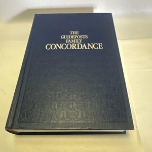 Peut inclure: Un livre à couverture rigide bleu marine intitulé "THE GUIDEPOSTS FAMILY CONCORDANCE" en lettres dorées. Le livre a une couverture texturée avec un motif répétitif. Les bords du livre sont bruns.