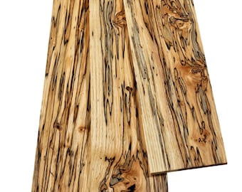 May include: Three rectangular wooden boards featuring a light tan base color with prominent, dark brown to black spalted grain patterns, swirling knots, and elongated streaks running vertically along the length of each piece.