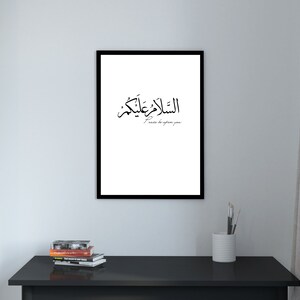 May include: A black framed print with white background featuring Arabic calligraphy that reads "Al-Salam Alaykum" in black, which translates to "Peace be upon you".