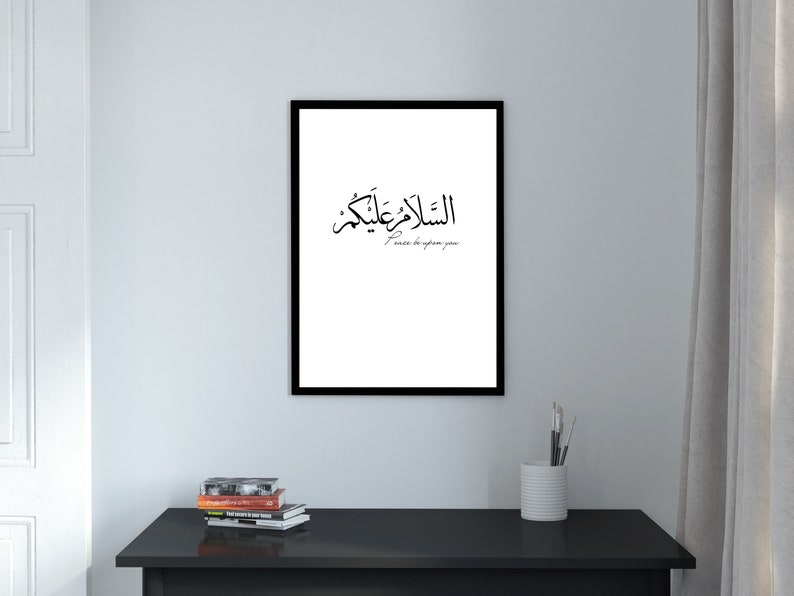 May include: A black framed print with white background featuring Arabic calligraphy that reads "Al-Salam Alaykum" in black, which translates to "Peace be upon you".