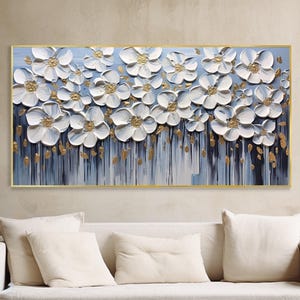 以下が含まれることがあります： 青と白の背景に金色のアクセントが施された白い花の絵画です。