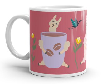 May include: A white ceramic mug with a red background featuring a cartoon llama holding a purple mug of coffee. The llama has a white body and a brown face. The mug has coffee beans inside. There are yellow flowers and a blue bird on the mug.