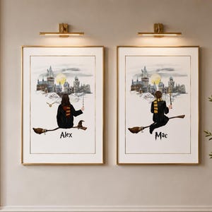 May include: Two framed art prints with gold frames, each depicting a person on a broomstick in front of a castle. The prints have the names "Alex" and "Mac" at the bottom. The background features a full moon.