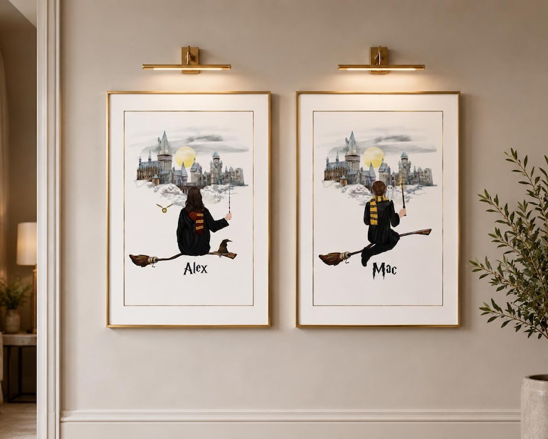 May include: Two framed art prints with gold frames, each depicting a person on a broomstick in front of a castle. The prints have the names "Alex" and "Mac" at the bottom. The background features a full moon.