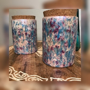 Op de afbeelding: Twee keramische potten met kurken deksels. De potten hebben een witte basis met een blauw en roze marmerpatroon.