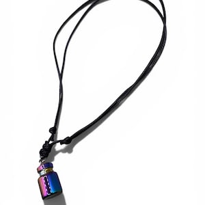 May include: A small, iridescent vial pendant necklace. The vial is a mix of blue, purple, and gold. It hangs from a black cord that is adjustable. The necklace is displayed against a white background.