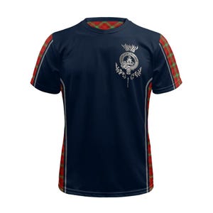 May include: A navy blue short-sleeved t-shirt with red and green plaid accents on the sleeves and collar. The shirt features a silver-colored thistle crest with a crest.