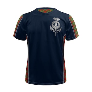 May include: A navy blue short-sleeved t-shirt with red and green plaid accents on the sleeves and collar. The shirt features a silver-colored crest with a thistle and the text "S'Bhoghail Mo Chre"