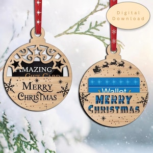 May include: Two round wooden Christmas ornaments with red ribbons, designed as gift card holders. The left ornament features star cutouts and the text "AMAZING GIFT CARD" and "MERRY CHRISTMAS". The right ornament shows a sleigh silhouette and "MERRY CHRISTMAS".