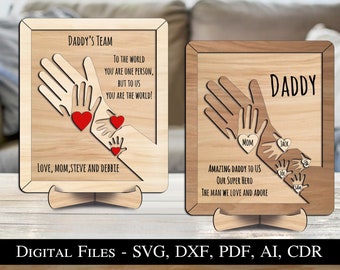 May include: Two wooden signs with a handprint design. The first sign says "Daddy's Team" and "To the world you are one person, but to us you are the world!" The second sign says "Daddy" and "Amazing Daddy to us, our super hero, the man we love and adore."