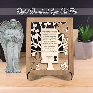 May include: Laser cut file design of a tree with hearts and doves, with a poem about remembering a loved one. The design is on a wooden frame with a stand. The text reads: "Though your smile is gone forever...Always in our thoughts, Forever in our hearts. Dearly loved and sadly missed. Bryan Wilson 2022"