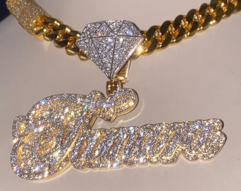 May include: A gold chain necklace with a diamond pendant featuring the name "Taurus" in cursive script.