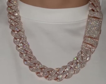 May include: A large, rose gold chain necklace with a Cuban link design. The chain is fully iced out with clear, sparkling stones.