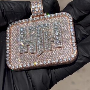 K&ouml;nnte beinhalten: Ein quadratischer Anh&auml;nger mit dem Wort "HUSTLE" in Diamanten. Der Anh&auml;nger ist aus Ros&eacute;gold gefertigt und mit klaren Diamanten besetzt.