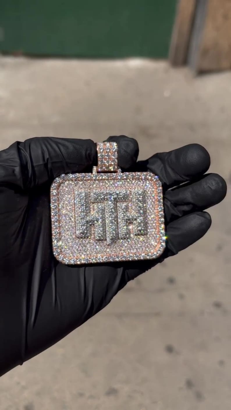 K&ouml;nnte beinhalten: Ein quadratischer Anh&auml;nger mit den Buchstaben "HT", die mit Diamanten besetzt sind und von einem ros&eacute;goldenen Rand umgeben sind.