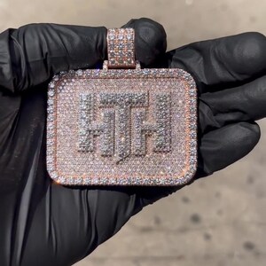 K&ouml;nnte beinhalten: Ein goldener Anh&auml;nger in quadratischer Form mit den Buchstaben "FTF", die mit Diamanten besetzt sind.