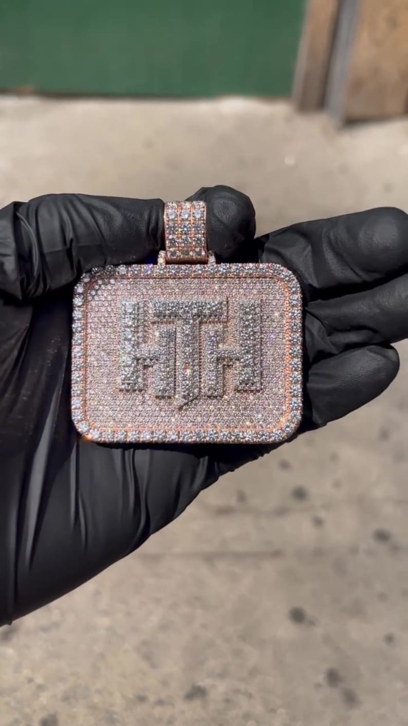 K&ouml;nnte beinhalten: Ein goldener Anh&auml;nger in quadratischer Form mit den Buchstaben "FTF", die mit Diamanten besetzt sind.