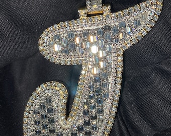 May include: A gold pendant in the shape of the letter "J" encrusted with baguette-cut diamonds.