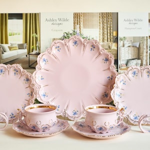 Peut inclure: Un ensemble de tasses à thé et de soucoupes à motifs floraux roses et bleus avec une grande assiette assortie. Les tasses à thé et les soucoupes ont un bord doré.