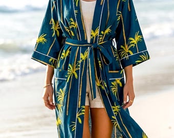 May include: A long, flowing robe in a deep teal color, adorned with a repeating pattern of yellow palm trees. The robe has a matching belt and white trim. The model is wearing a white top and shorts.