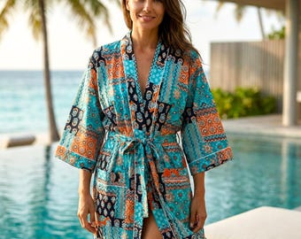 May include: A patterned turquoise robe with orange and navy accents. The robe has a tie waist and white trim. The image shows the robe being worn near a pool and palm trees.
