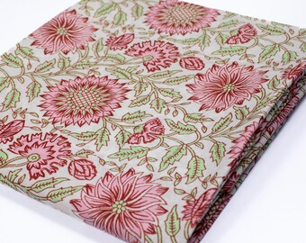 Pode incluir: Um pedaço de tecido dobrado com uma estampa floral. O tecido é branco com flores rosa e vermelhas e folhas verdes.