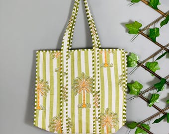 May include: A rectangular tote bag featuring a vertical green and white striped pattern with a repeating orange and green palm tree motif. The bag includes two matching striped shoulder straps and a quilted texture throughout the fabric surface.