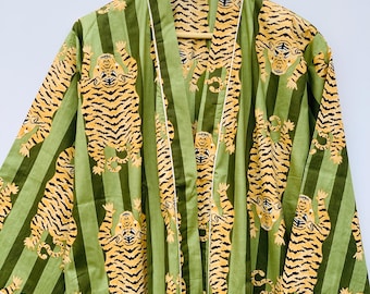 May include: Green striped robe with a repeating pattern of orange and black tigers. The robe has a shawl collar, pockets, and white trim. It is hanging on a wooden hanger.