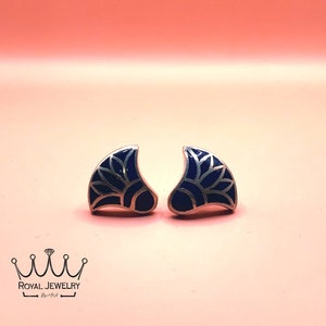May include: A pair of silver earrings with a blue enamel design. The design is a stylized flower with a silver outline.