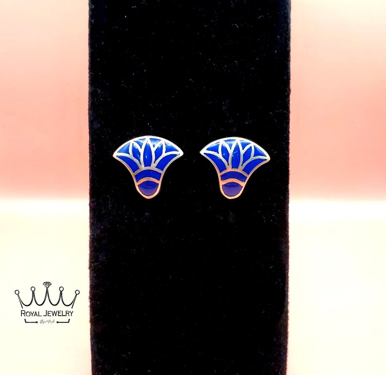May include: A pair of silver stud earrings with a blue enamel design. The design is a stylized flower with a silver outline.