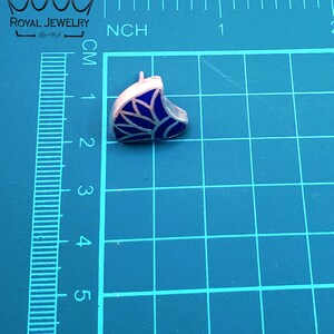 May include: A silver earring with a blue enamel design. The design is a stylized leaf with a white outline.