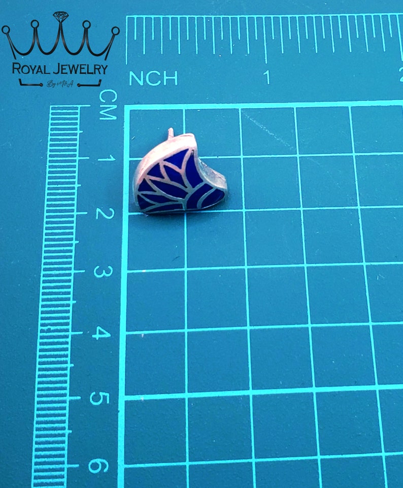 May include: A silver earring with a blue enamel design. The design is a stylized leaf with a white outline.