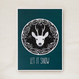 Weihnachtspostkarte mit Illustration von einem Reh in verschneitem Wald und Pilzen mit Spruch "Let ist Snow"/ away with reality