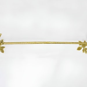 Op de afbeelding: Gouden metalen handdoekrek met vogel- en bladerenaccenten aan beide uiteinden.