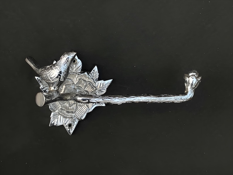 Peut inclure: Porte-papier toilette argent&eacute; avec un motif d'oiseau et de fleurs. Le porte-papier est mont&eacute; sur un mur.