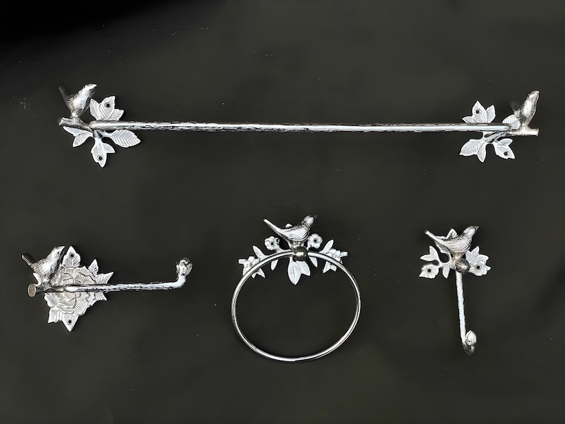 Peut inclure: Un ensemble de salle de bain en argent avec une barre &agrave; serviettes, un porte-papier toilette, un anneau &agrave; serviettes et un crochet. Chaque pi&egrave;ce pr&eacute;sente un oiseau d&eacute;coratif perch&eacute; sur une branche.