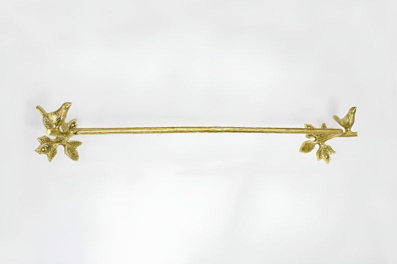 Op de afbeelding: Gouden metalen handdoekrek met vogel- en bladerenaccenten aan beide uiteinden.