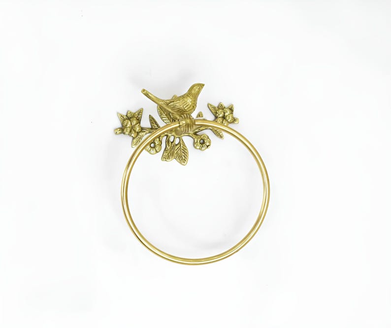 Op de afbeelding: Gouden metalen handdoekring met een vogel die op een tak zit met bladeren en bloemen.