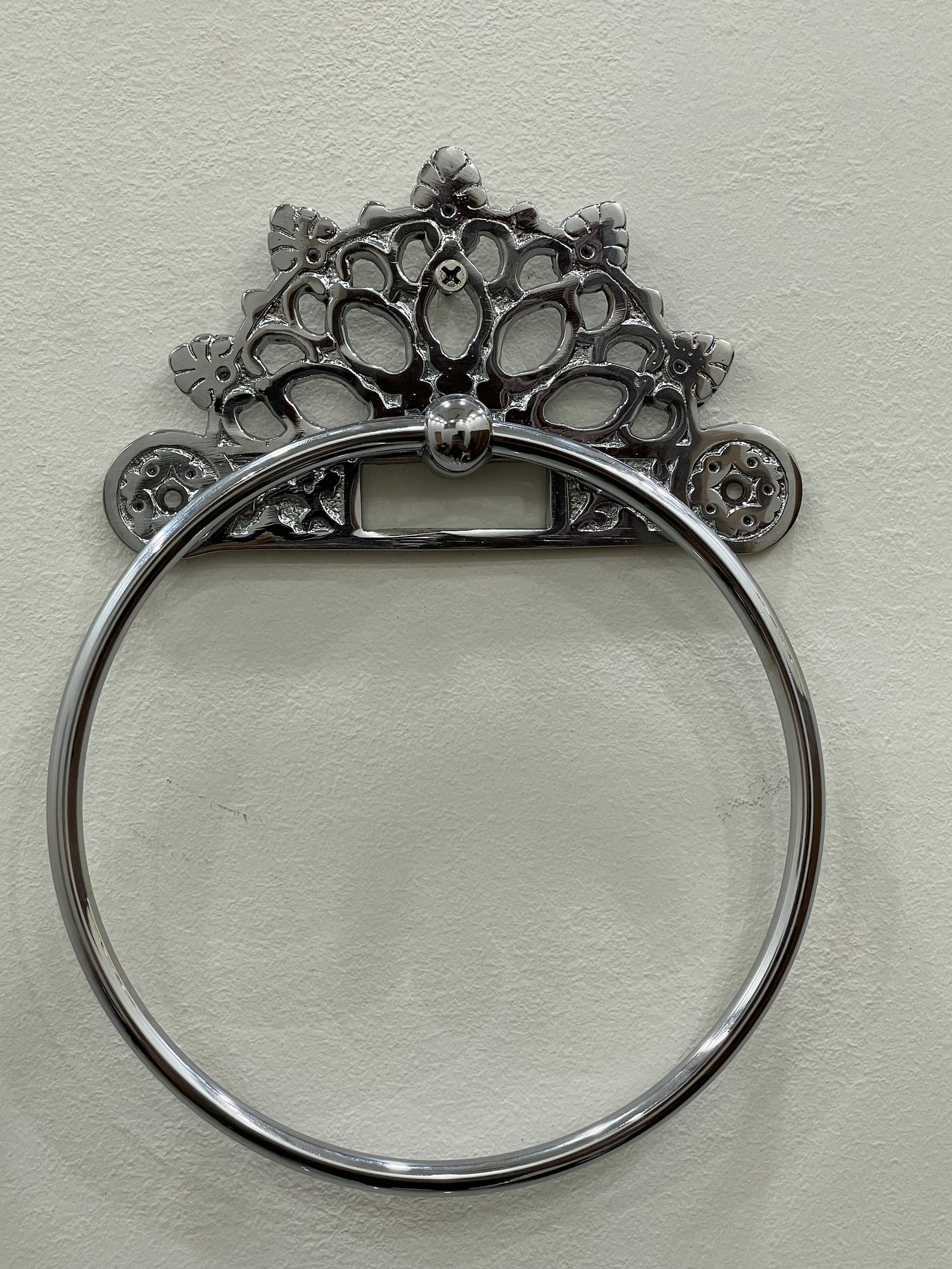 Victorian chrome towel ring with ornate floral-style backplate mounted on a white wall