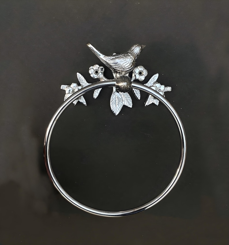 Peut inclure: Porte-serviette en m&eacute;tal argent&eacute; avec un motif d'oiseau et de fleurs. L'anneau est circulaire et le motif est fix&eacute; au sommet de l'anneau.