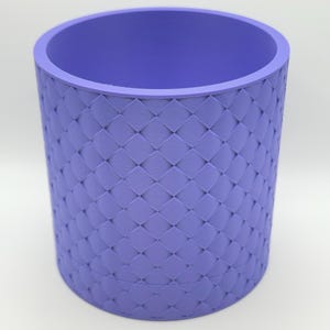 May include: A purple cylindrical planter with a woven diamond pattern.