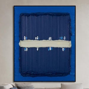 May include: A large rectangular wall art piece featuring a deep blue textured background with a horizontal beige brushstroke across the center. Small, stylized white and blue boat shapes are arranged in a line along the beige stripe.