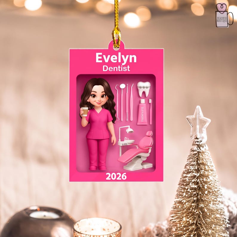 May include: A rectangular pink ornament featuring the name Evelyn and the title Dentist. It displays a cartoon character in pink scrubs holding a coffee cup, alongside dental tools, a tooth with braces, toothpaste, and a dental chair, with 2026.