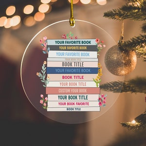 May include: A round, clear ornament with a stack of books with floral accents. The books have the text "YOUR FAVORITE BOOK" repeated multiple times and "BOOK TITLE" repeated multiple times.