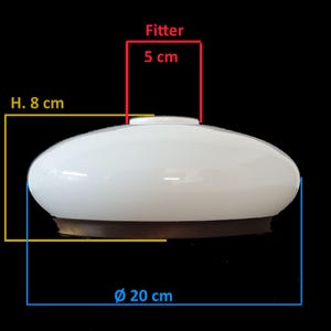 Könnte beinhalten: Weißer, ovaler Lampenschirm aus Glas mit einem Durchmesser von 20 cm und einer Höhe von 8 cm. Der Fitter ist 5 cm. Der Lampenschirm hat einen braunen Sockel und ist vor schwarzem Hintergrund platziert.